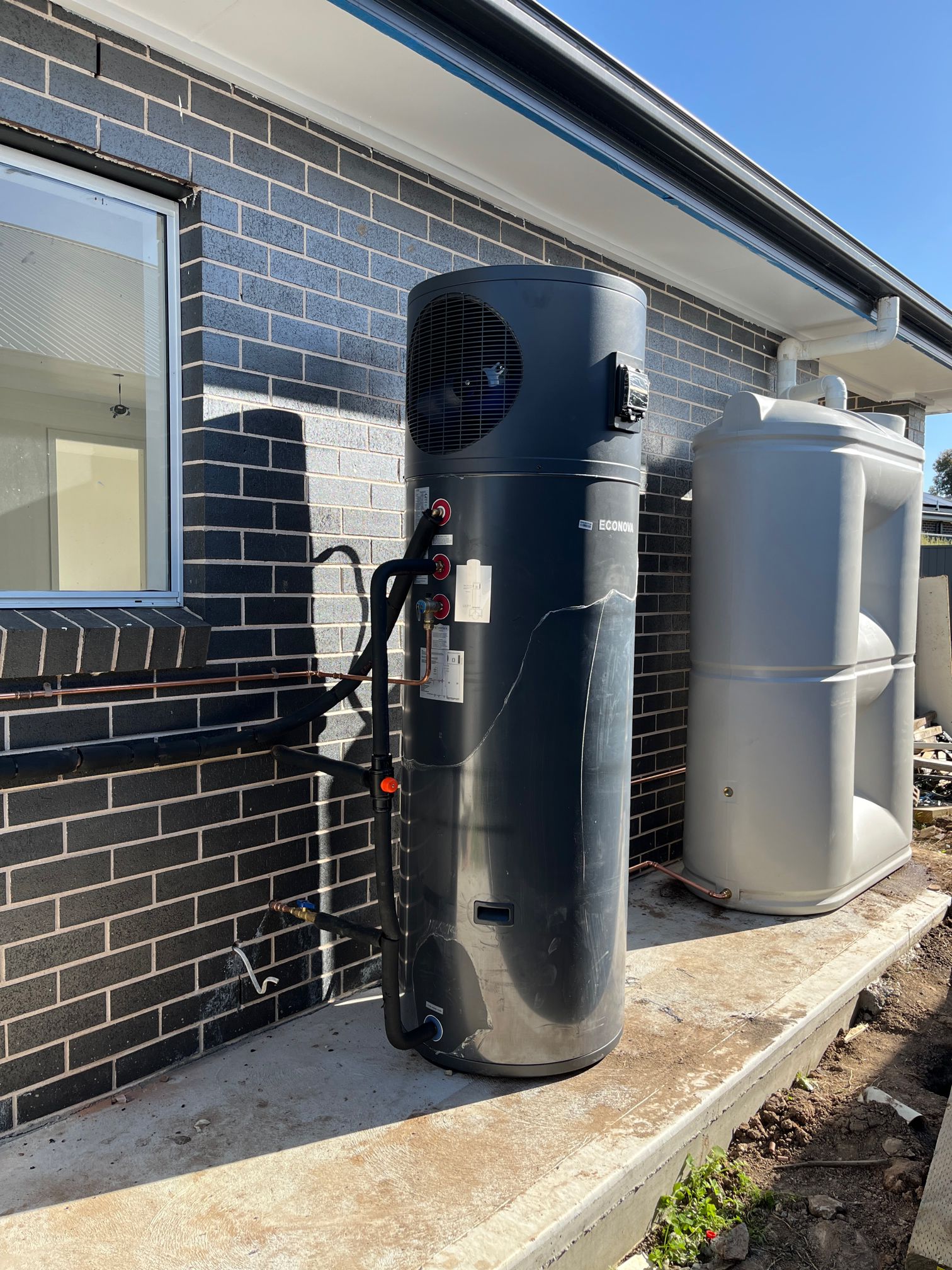 Econova all-in-one heat pump hot water system installed outside a brick home in Sydney by TM Pro Plumbing