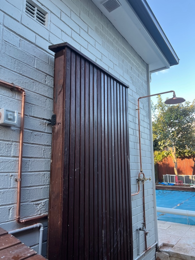Copper shower mounted on the outside of a building