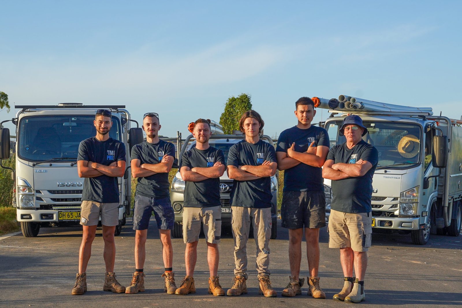 The TM Pro Plumbing team lined up in front of their vans