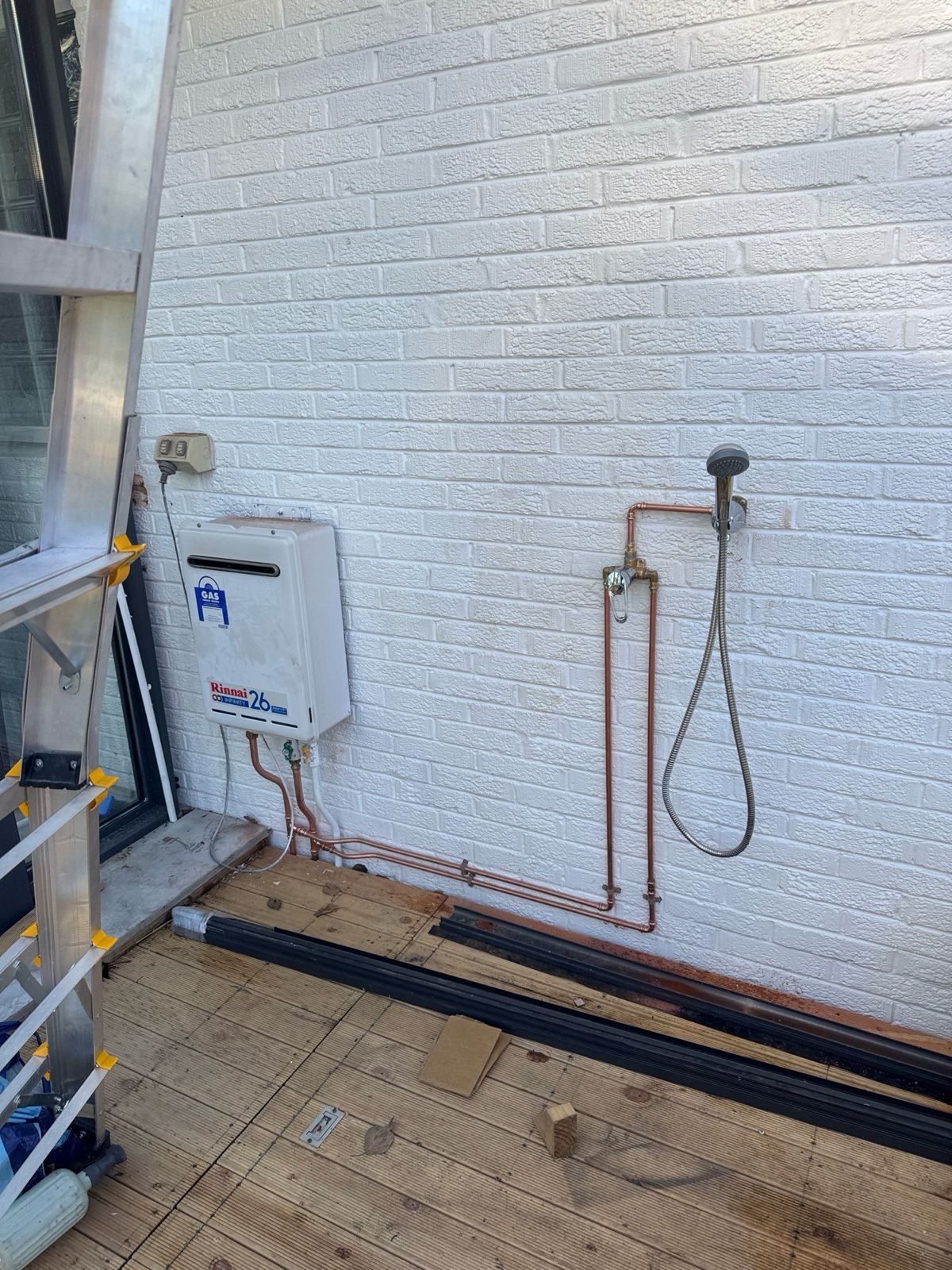 Budget outdoor shower and bath setup on an exterior wall