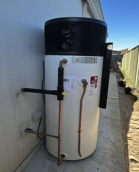 Stiebel Eltron all-in-one heat pump hot water system installed in a side passage by TM Pro Plumbing, with insulated pipework and a tempering valve