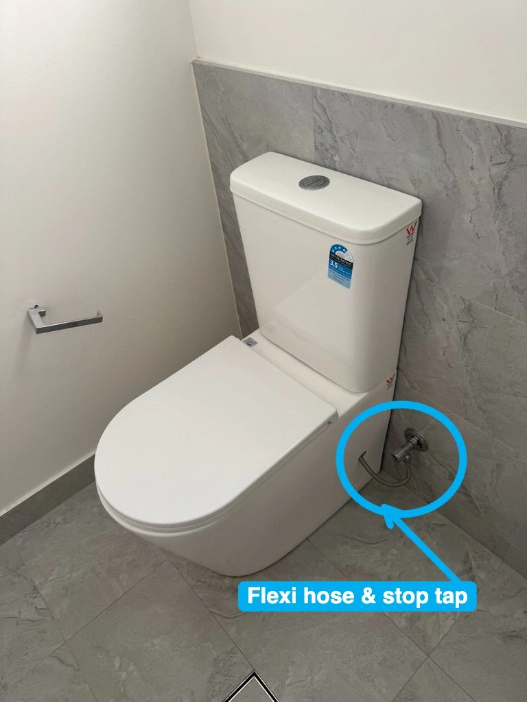 Toilet cistern with a bottom inlet, visible flexible hose and stop tap beside the pan