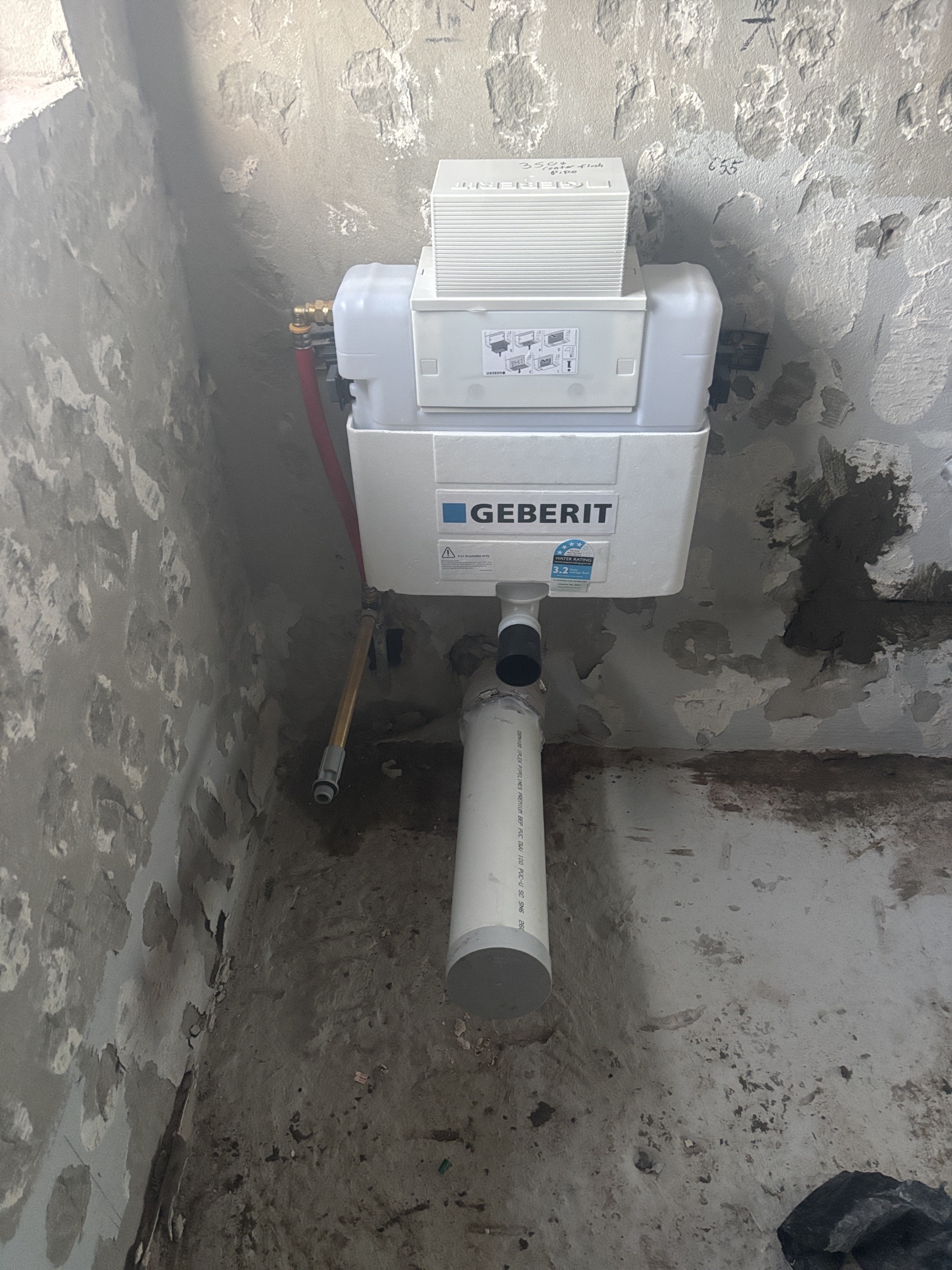 Geberit concealed cistern and toilet drainage installed against a stripped bathroom wall