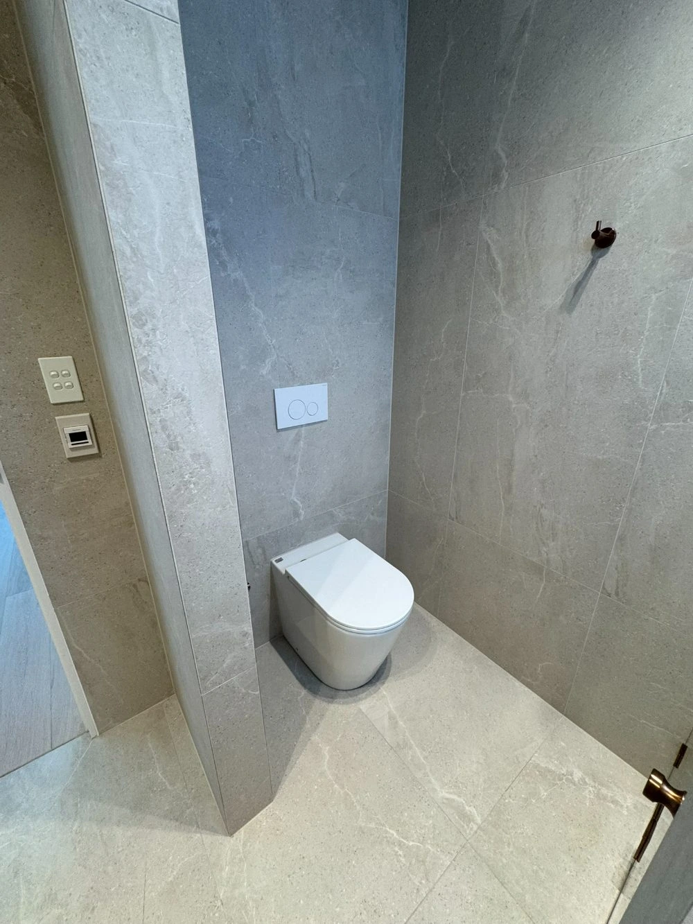 Finished floor-standing toilet with an in-wall concealed cistern and dual-flush plate