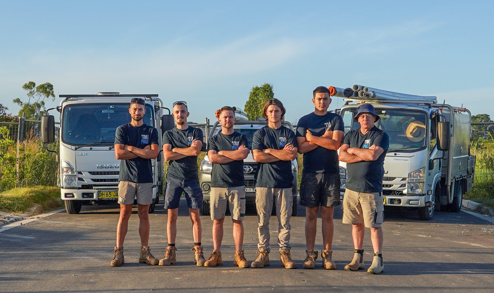 TM Pro Plumbing crew standing in front of their work vehicles