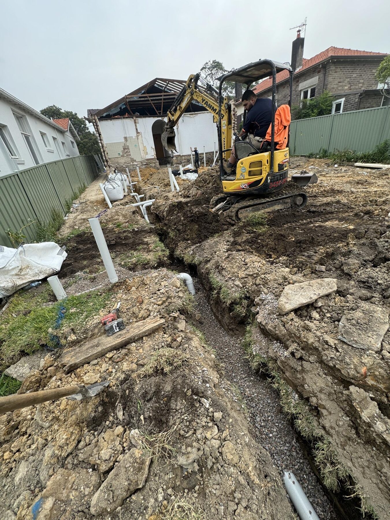 Large extension groundworks with excavator and drainage pipework in trenches