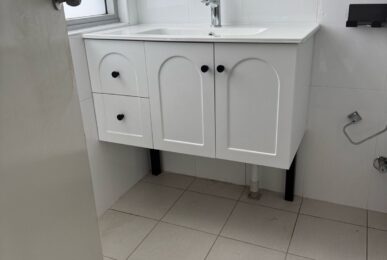 Newly installed white bathroom vanity and mirrored shaving cabinet in a Wolli Creek unit by TM Pro Plumbing.